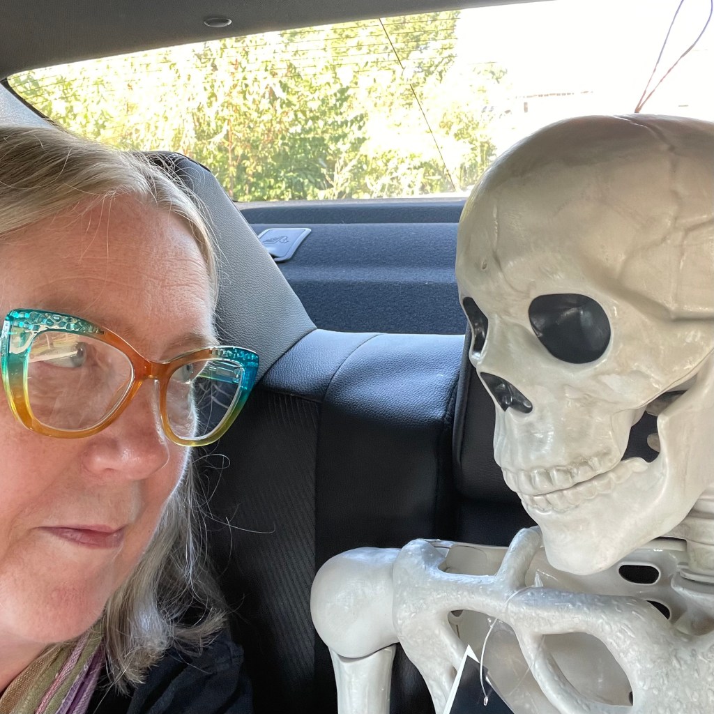 photo of a woman sitting in a car talking to a plastic skeleton