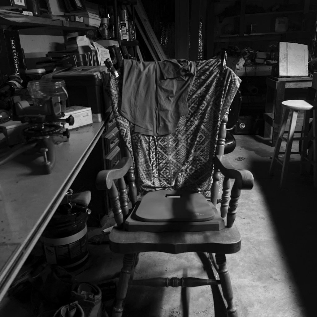Black and white photo of a rocking chair in a garage.